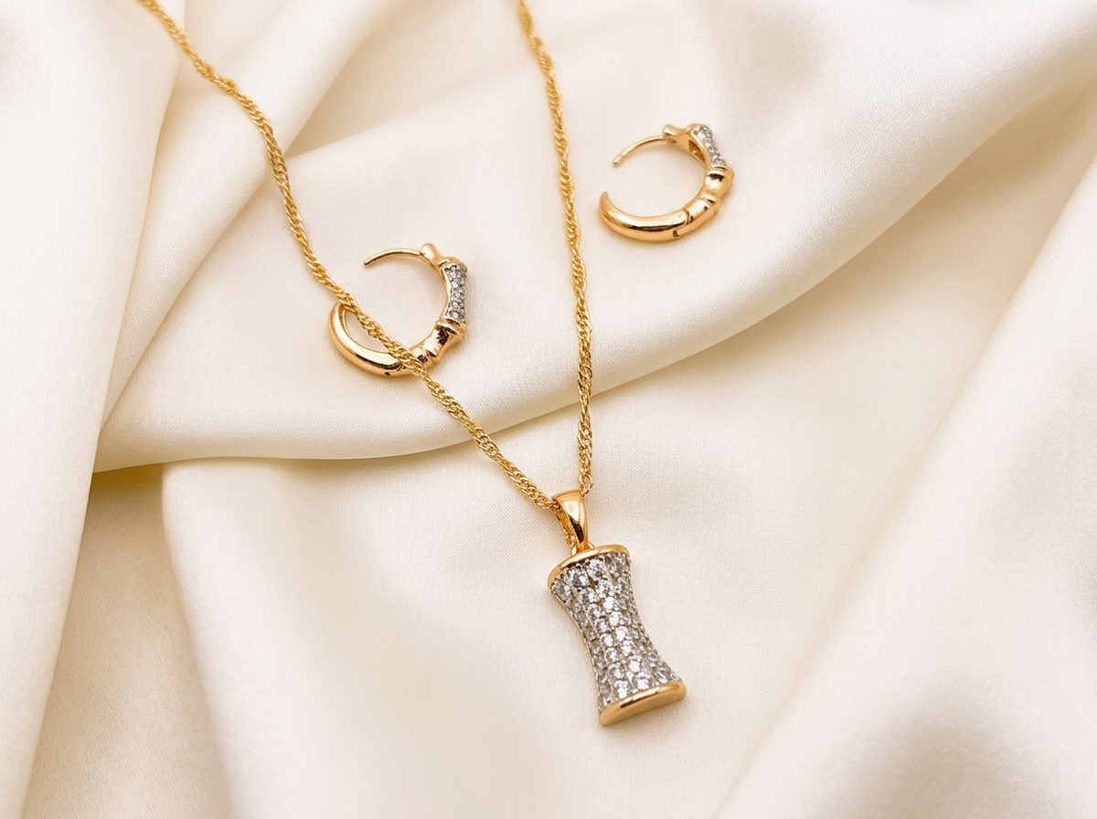 Bin Maqsood bamboo-style pendant and earring set on ivory silk fabric.