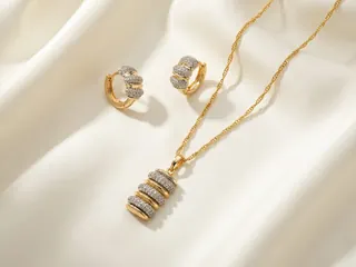 Pendant Sets — Bin Maqsood gold-tone cylinder pave pendant necklace with matching earrings on ivory silk.